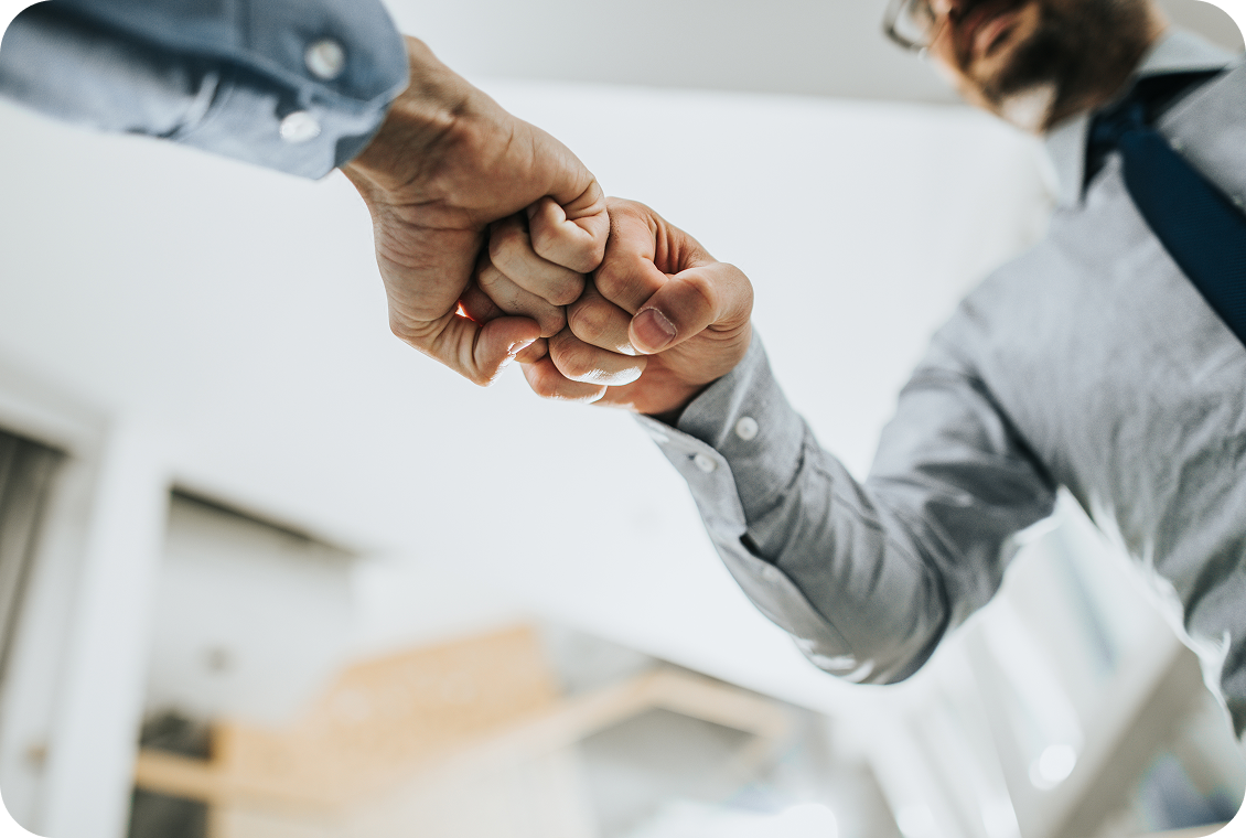 Two people fist bumping in office.