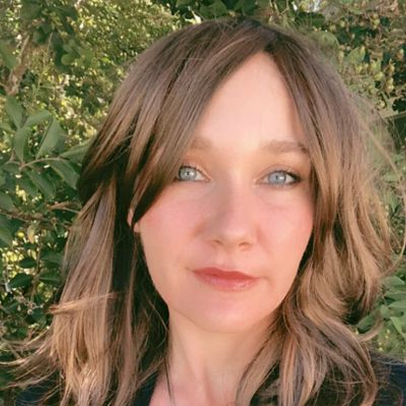 Woman outdoors with green foliage background.