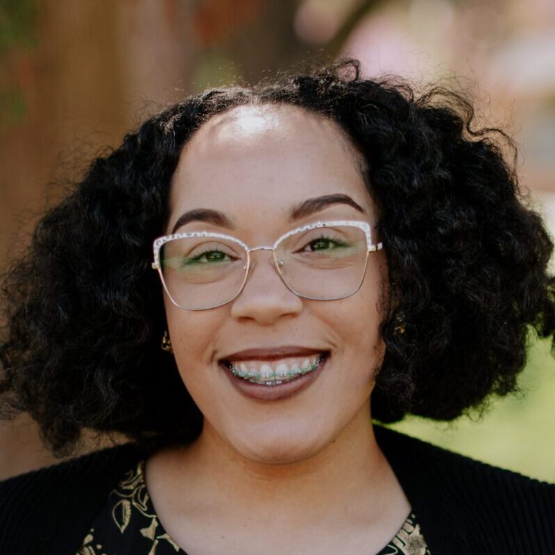 Smiling woman with long hair and glasses outdoors