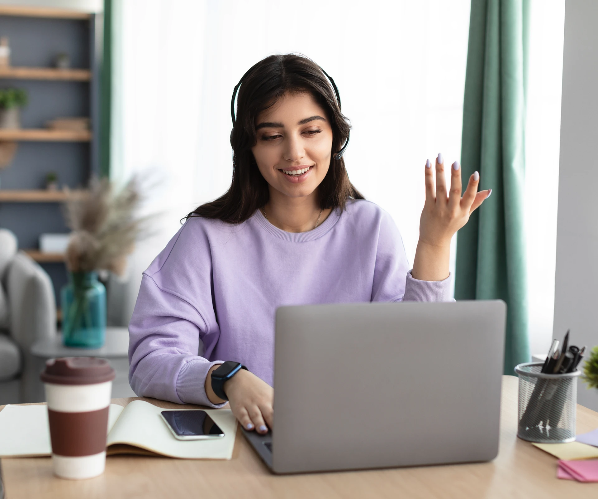 Woman using laptop at home, wearing headphones.
